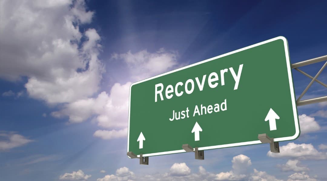 "Recovery Just Ahead" displayed on green billboard.