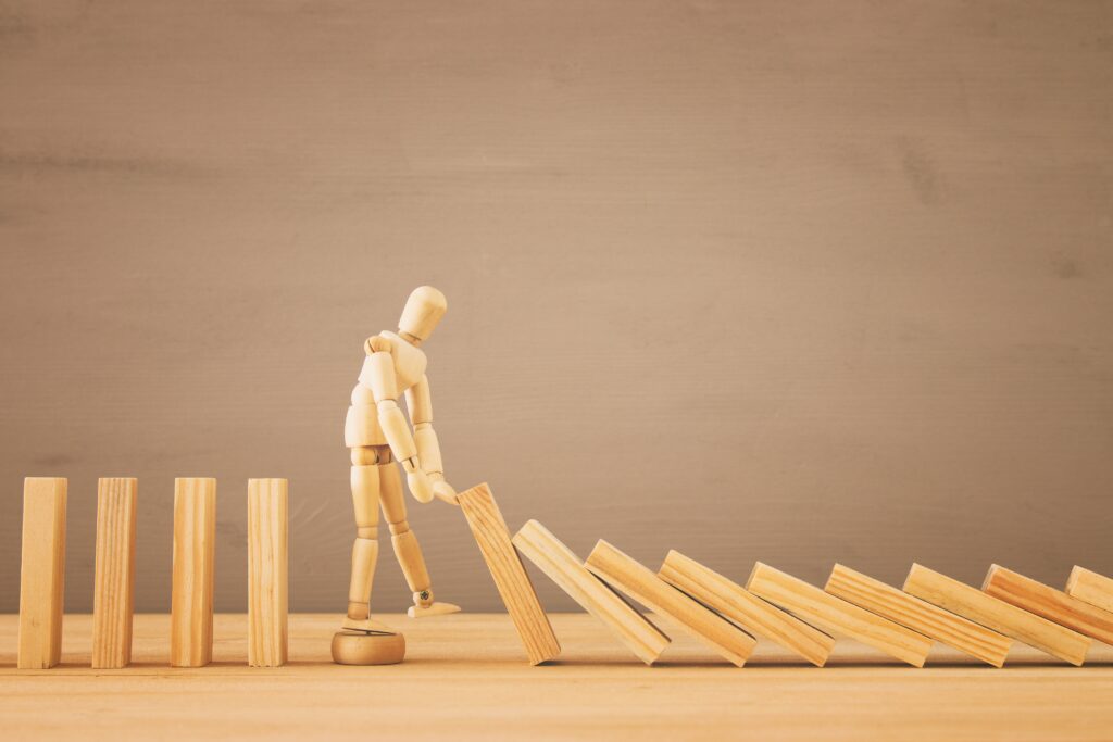 A wooden lay figure stopping the effect of wooden blocks domino.