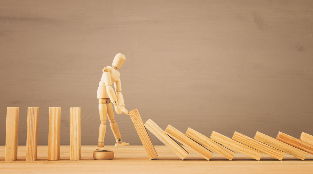 A wooden lay figure stopping the effect of wooden blocks domino.