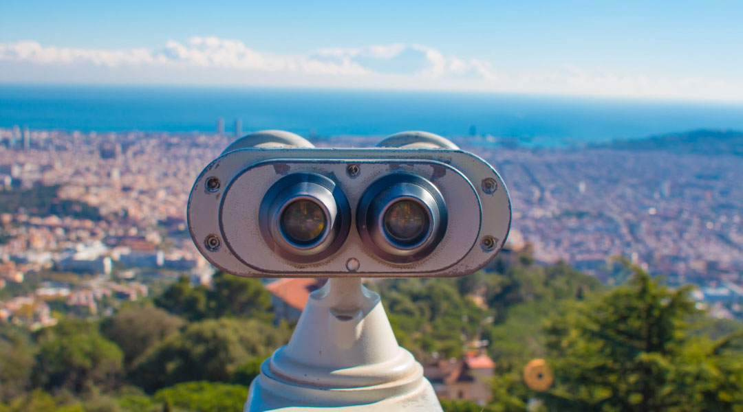 Stationary binoculars looking down over a city's scenery.